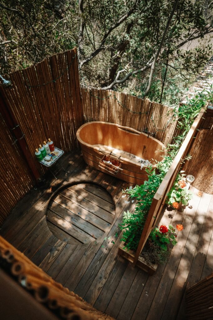 une salle de bains design exterieur sur une terrasse au milieu des arbres avec une baignoire en bois et un espace douche tout en bois