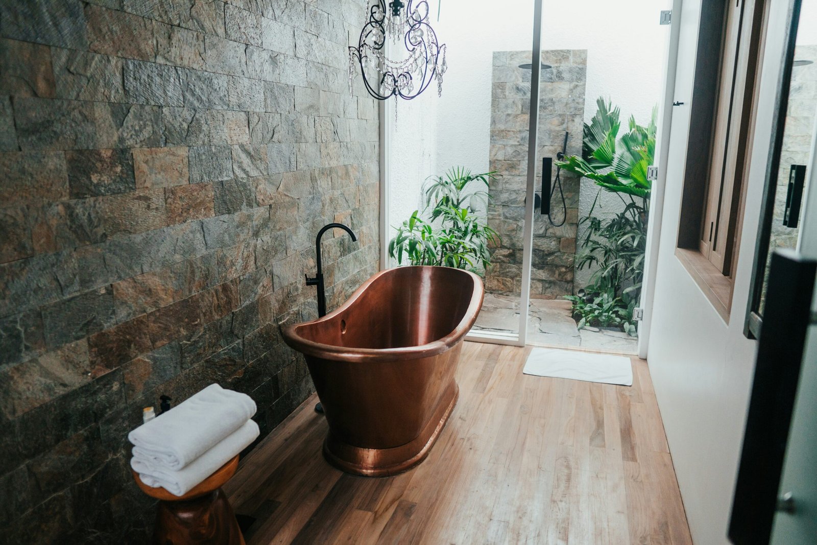 une salle de bain exotique a Toulon avec baignoire en cuivre et douche extérieur en pierre